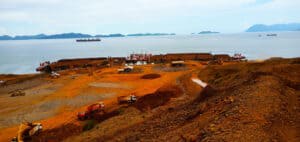 View of nickel ore being loaded off the island of South Sulawesi, Indonesia, featuring ground, trees, sea, sky