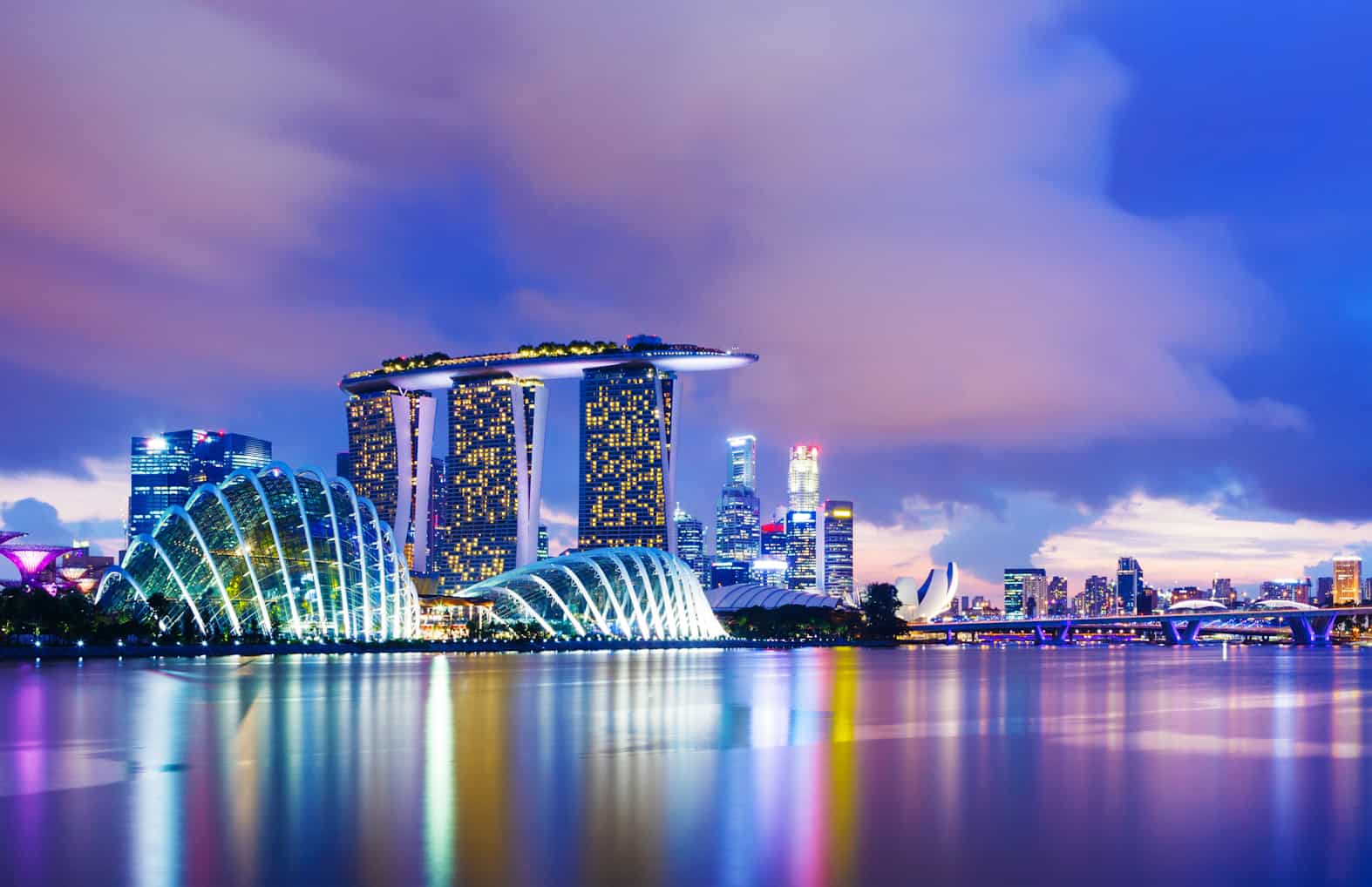Singapore waterfront skyline, featuring sunset sky and light reflections on water. Image by ESB Professional at Shuttestock