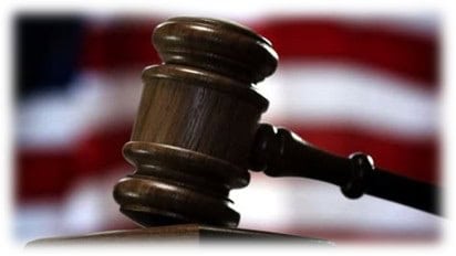 A wooden gavel, striking a surface