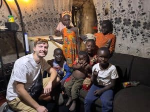 A young male medical student surrounded by Zambian children in a tent