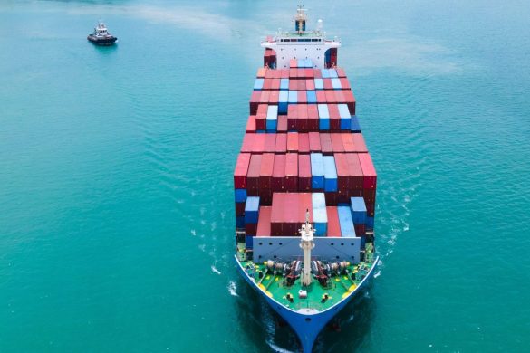 Cargo vessel loaded with shipping containers leaving a seaport - aerial picture by Time Stopper at SHutterstock