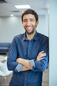Guilherme Braga, Founder/CEO Egalite, a young man with blue eyes, brown hair and neatly trimmed beard, wearing a denim shirt