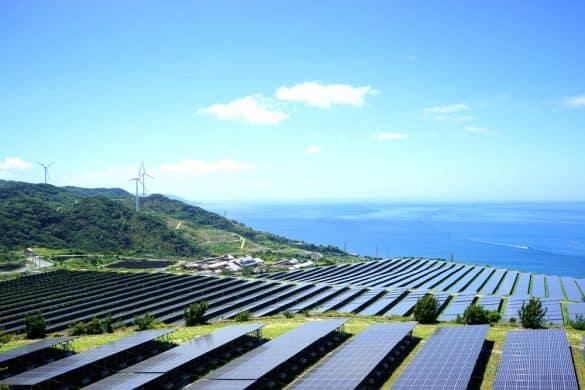 Solar farm with solar panels pointed upwards towards teh sun on a hillside, image by maroke at Shutterstock