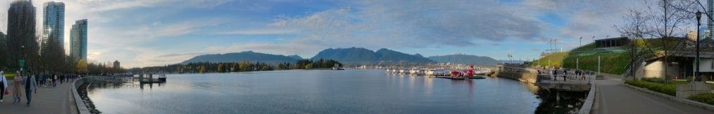 Panorama view of Vancouver with sea bay, boats and city in the background, against a blue sky