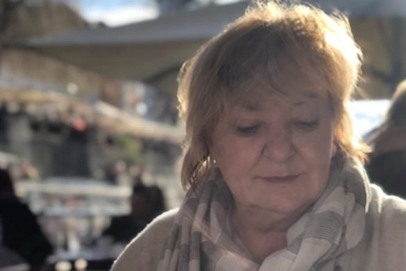 Head and shoulders photo of Margaret (Maggie) Mikulski, a woman with short light auburn hair, wearing a brey and white scarf, looking downwards right.